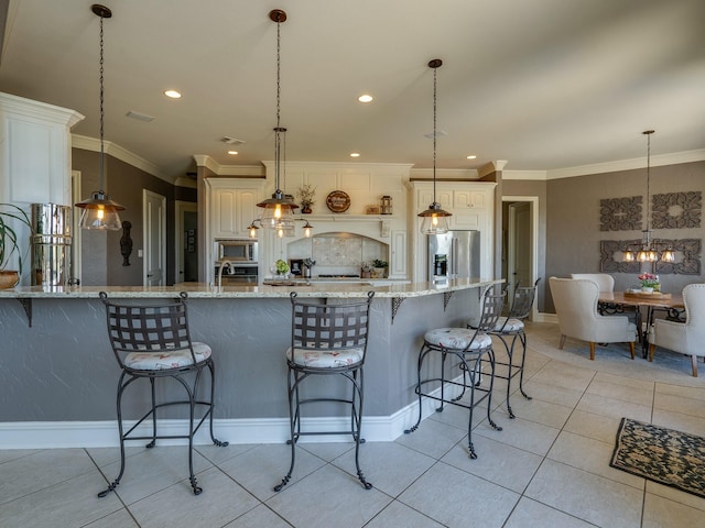 kitchen featuring pendant lighting, appliances with stainless steel finishes, a kitchen breakfast bar, and light stone counters