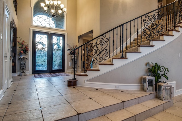 tiled entrance foyer featuring french doors, a chandelier, and a high ceiling