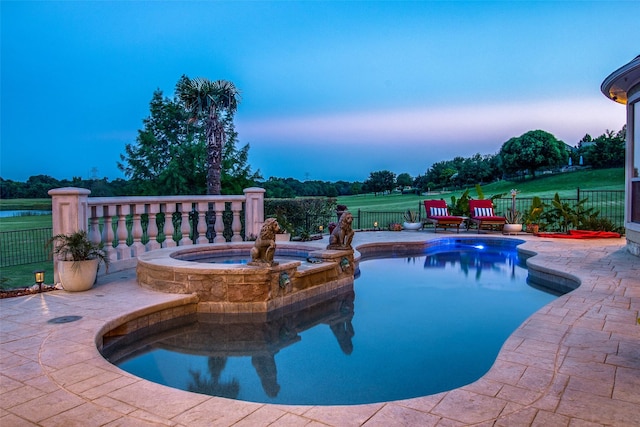 pool at dusk featuring an in ground hot tub and a patio