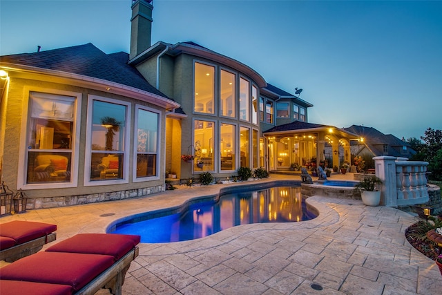 back house at dusk featuring a patio