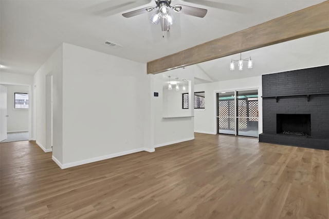 unfurnished living room with hardwood / wood-style flooring, a brick fireplace, vaulted ceiling with beams, and ceiling fan