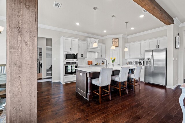 kitchen featuring built in microwave, stainless steel oven, a center island with sink, custom range hood, and pendant lighting