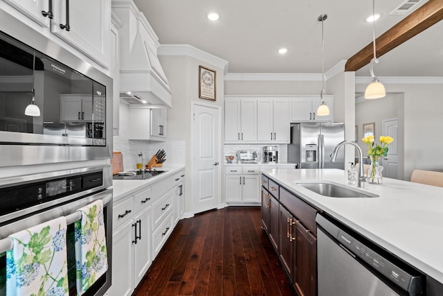 kitchen with sink, white cabinetry, hanging light fixtures, custom range hood, and stainless steel appliances