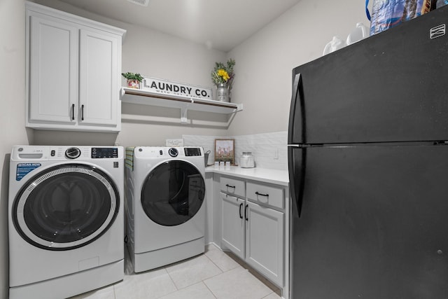 clothes washing area with light tile patterned floors, cabinets, and washing machine and clothes dryer