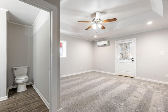 carpeted empty room featuring ornamental molding, a wall mounted AC, ceiling fan, and a tray ceiling