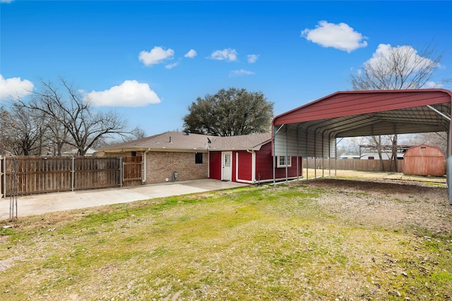 back of property with a carport, a lawn, and a storage unit