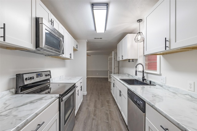 kitchen with appliances with stainless steel finishes, sink, hanging light fixtures, and white cabinets