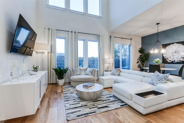 living room with a high ceiling, a notable chandelier, and light hardwood / wood-style floors