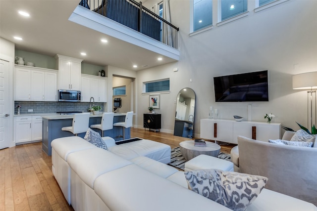 living room with light hardwood / wood-style floors and a high ceiling