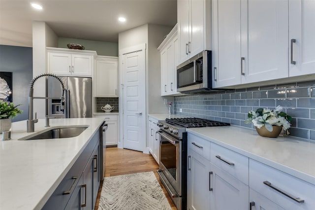 kitchen featuring white cabinetry, sink, backsplash, and appliances with stainless steel finishes