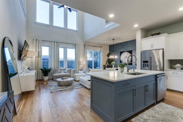 kitchen with appliances with stainless steel finishes, decorative light fixtures, an island with sink, sink, and white cabinets