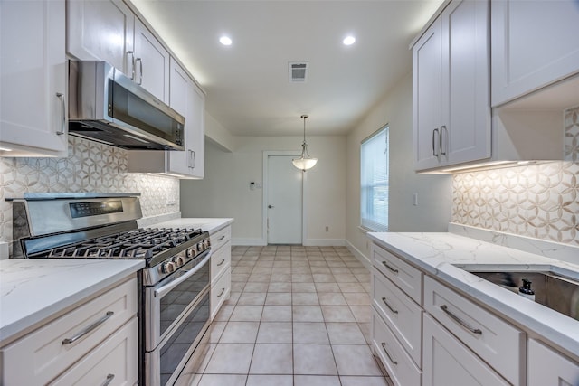 kitchen featuring appliances with stainless steel finishes, pendant lighting, white cabinets, and light stone counters