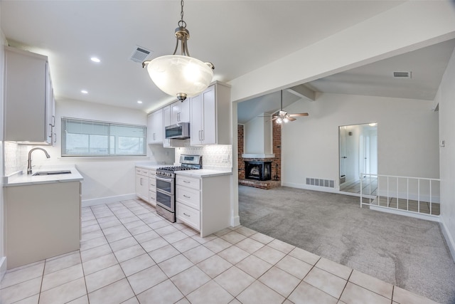 kitchen with appliances with stainless steel finishes, white cabinetry, vaulted ceiling with beams, tasteful backsplash, and light carpet