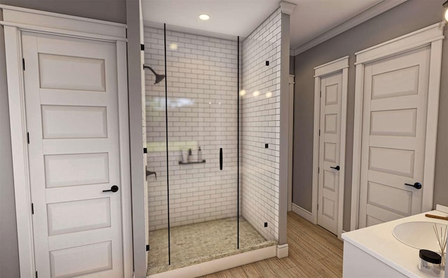 bathroom with vanity, hardwood / wood-style floors, crown molding, and a shower with shower door