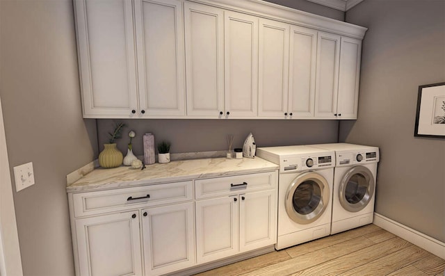 laundry room with cabinets, washer and dryer, and light wood-type flooring