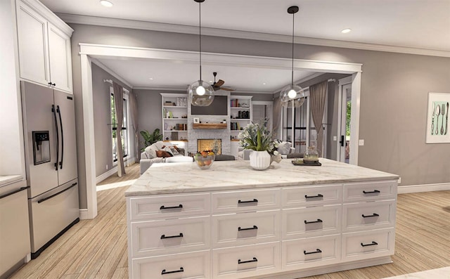 kitchen featuring a center island, hanging light fixtures, stainless steel fridge, light stone countertops, and white cabinets