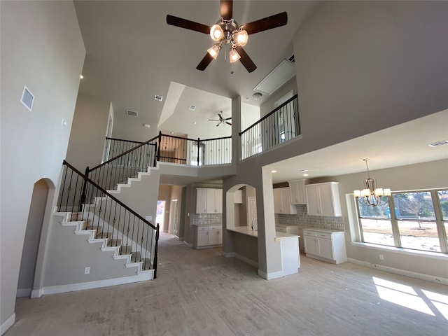 unfurnished living room featuring sink, ceiling fan with notable chandelier, and light hardwood / wood-style flooring