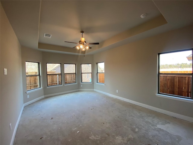 empty room with plenty of natural light, a raised ceiling, and ceiling fan