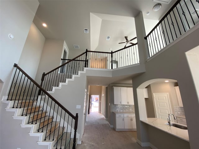 stairs with sink, a towering ceiling, and ceiling fan