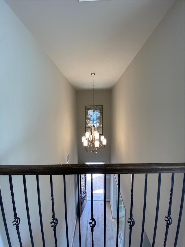 staircase featuring concrete flooring and a chandelier