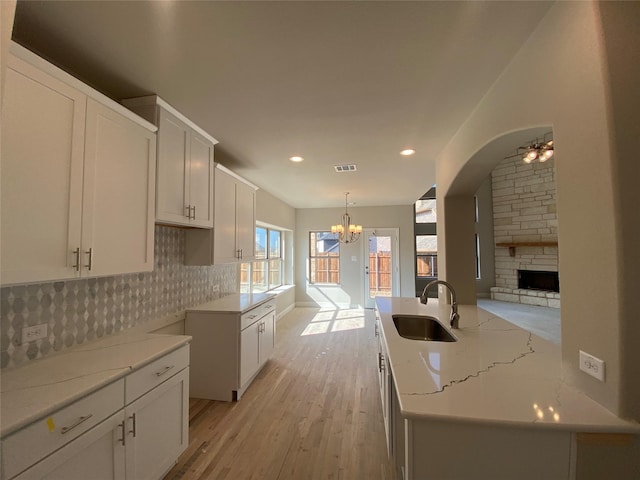 kitchen with sink, tasteful backsplash, decorative light fixtures, a center island, and white cabinets