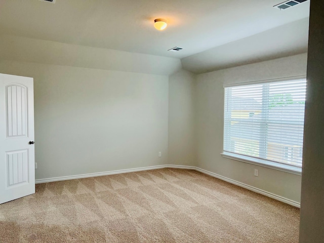 empty room featuring vaulted ceiling and light colored carpet