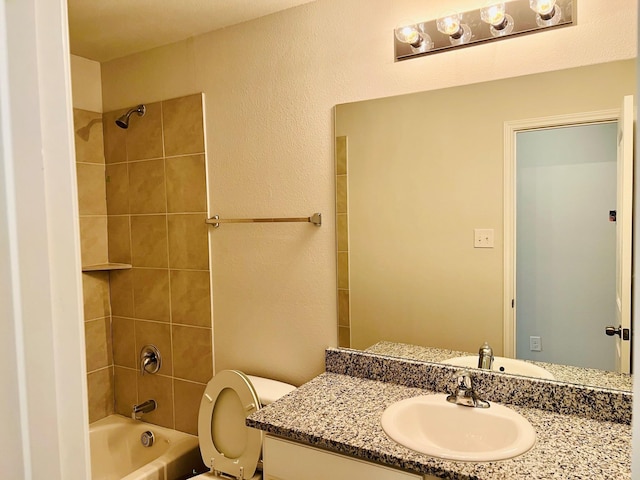 full bathroom with tiled shower / bath, vanity, and toilet