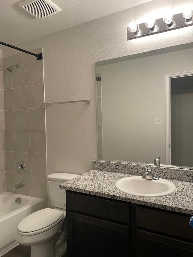 full bathroom featuring vanity, tiled shower / bath, and toilet