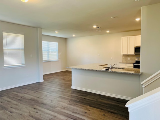 kitchen with appliances with stainless steel finishes, white cabinetry, sink, backsplash, and light stone countertops