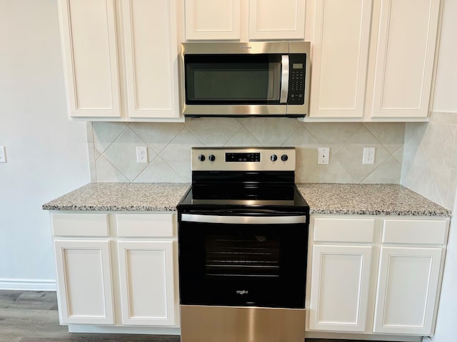 kitchen featuring light stone countertops, stainless steel appliances, and white cabinets