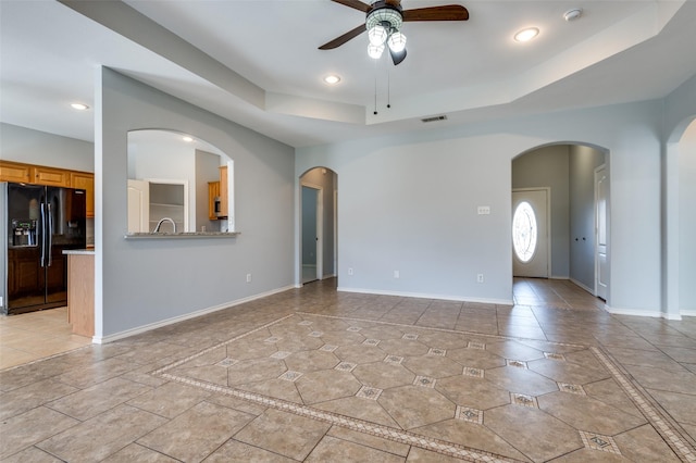 tiled empty room with a tray ceiling and ceiling fan