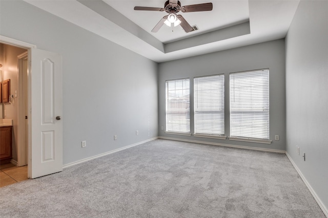 carpeted spare room featuring ceiling fan and a raised ceiling