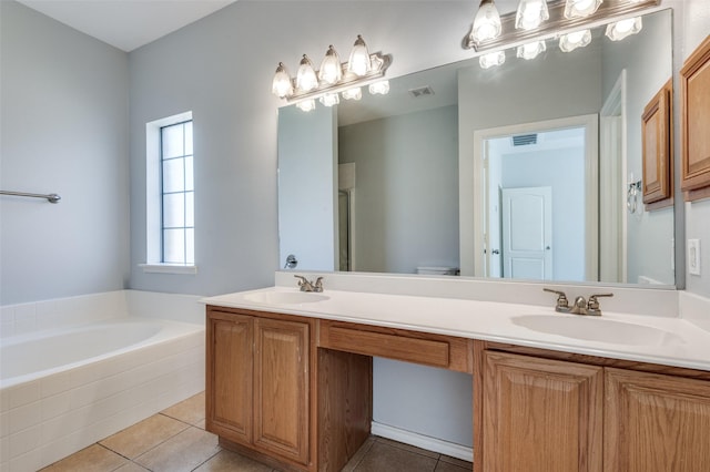 bathroom featuring tile patterned flooring, tiled tub, vanity, and toilet