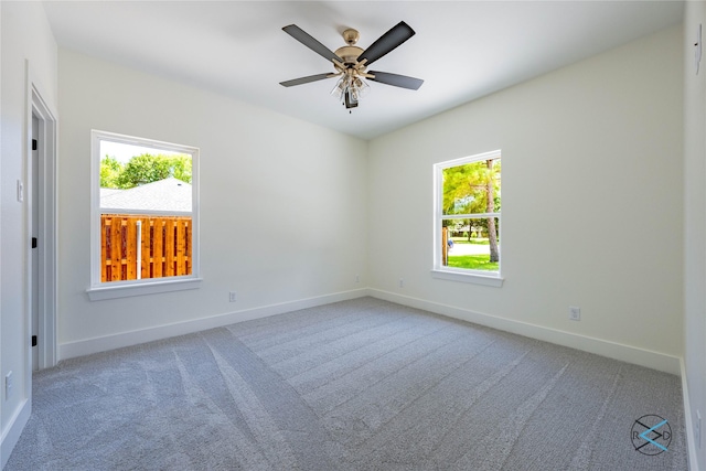 carpeted empty room featuring baseboards and a ceiling fan