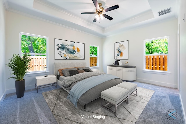 carpeted bedroom with ceiling fan, ornamental molding, and a raised ceiling