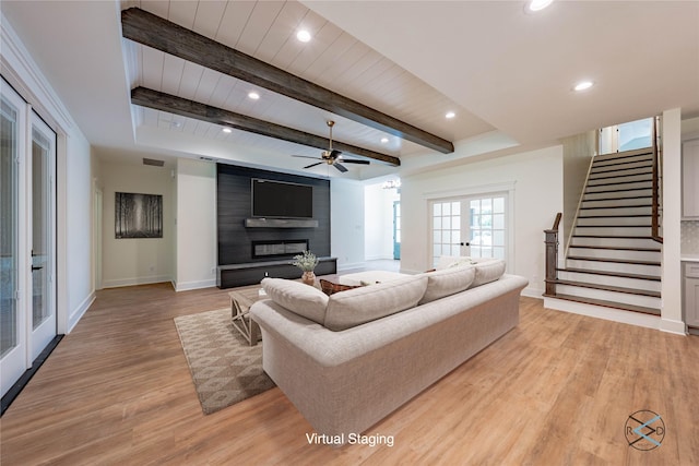 living room featuring french doors, a fireplace, light hardwood / wood-style floors, and beam ceiling