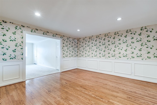 empty room with crown molding and light hardwood / wood-style floors