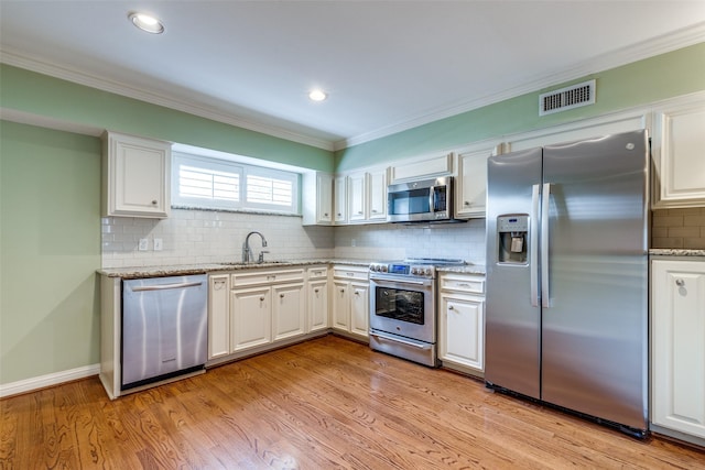 kitchen with stainless steel appliances, ornamental molding, sink, and white cabinets