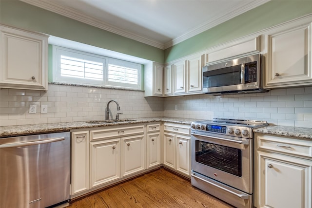 kitchen featuring sink, light hardwood / wood-style flooring, ornamental molding, appliances with stainless steel finishes, and white cabinets