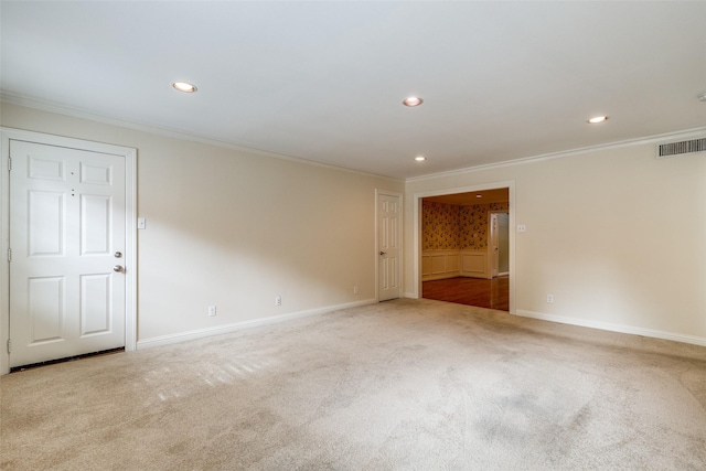 empty room featuring crown molding and light colored carpet