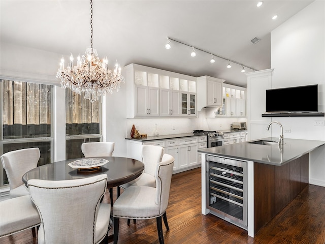 kitchen with high end stainless steel range, sink, white cabinetry, kitchen peninsula, and beverage cooler