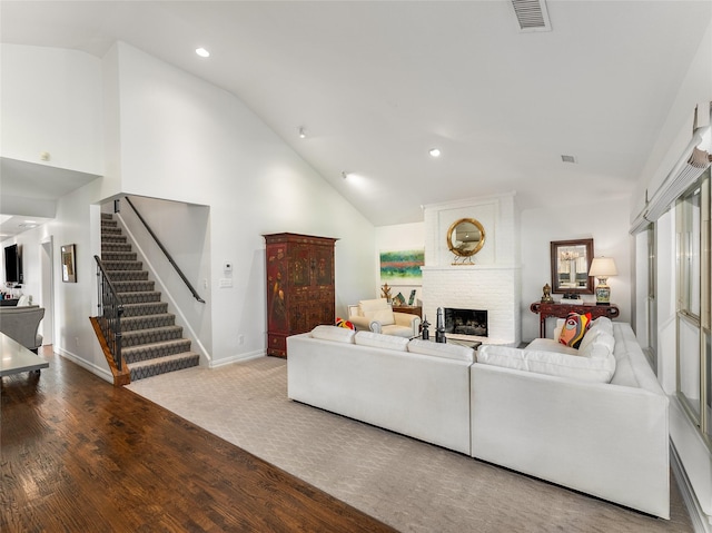 living room featuring wood-type flooring, a fireplace, and high vaulted ceiling