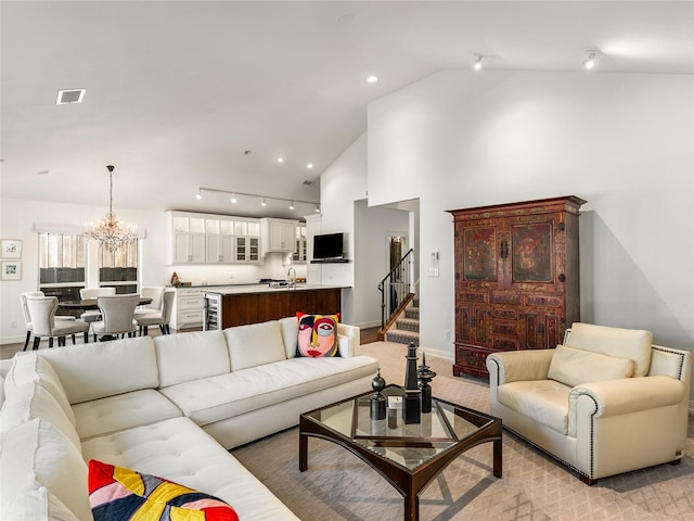 living room featuring rail lighting, sink, a chandelier, high vaulted ceiling, and beverage cooler