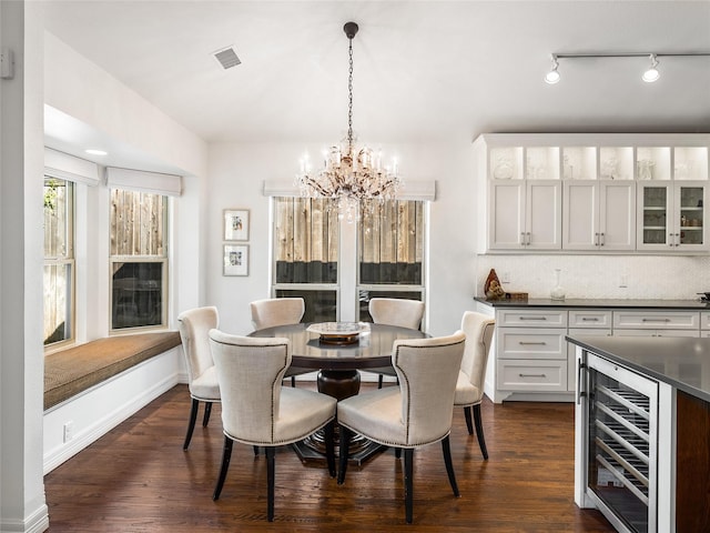 dining space featuring a notable chandelier, dark wood-type flooring, and beverage cooler