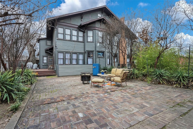 rear view of property featuring a wooden deck, an outdoor living space with a fire pit, and a patio