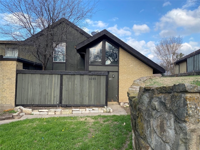 view of property exterior featuring brick siding and a lawn