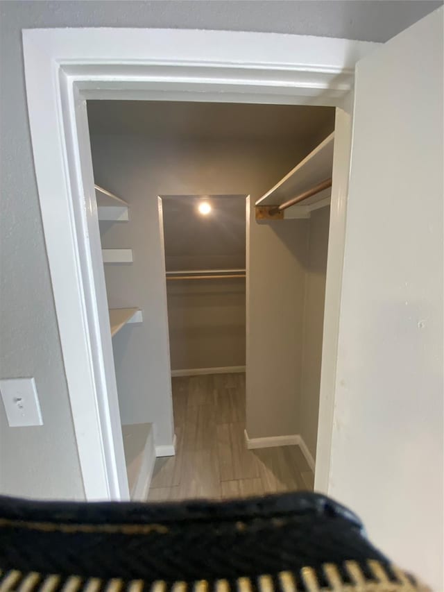 walk in closet with wood finished floors