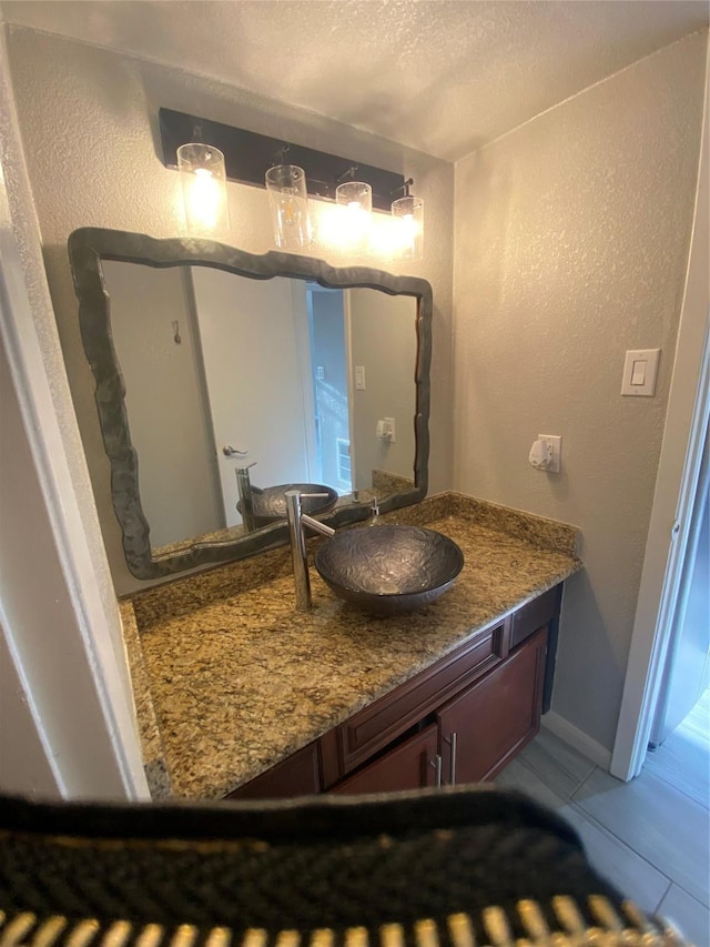 bathroom with a textured wall, tile patterned flooring, a textured ceiling, and vanity