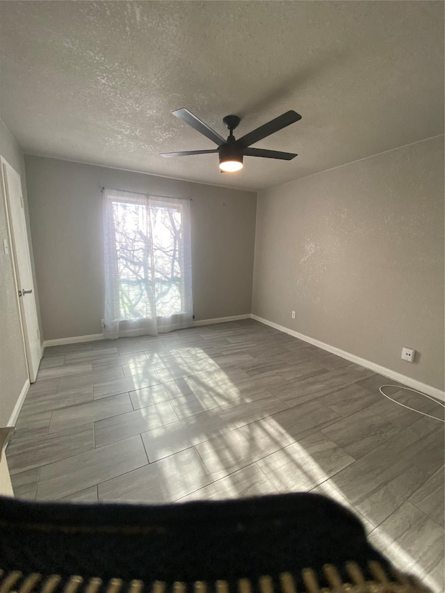 unfurnished room with ceiling fan and a textured ceiling