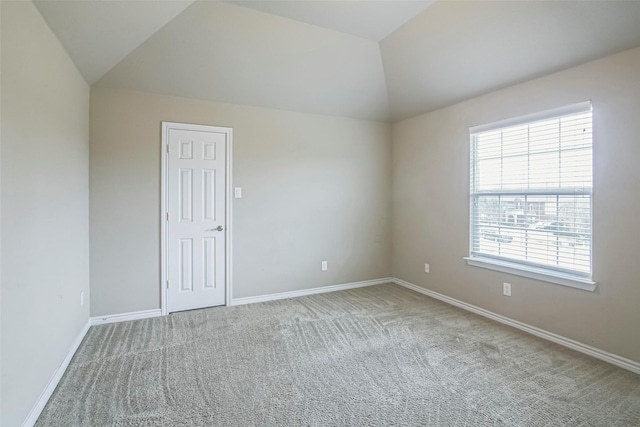 spare room featuring carpet floors and vaulted ceiling